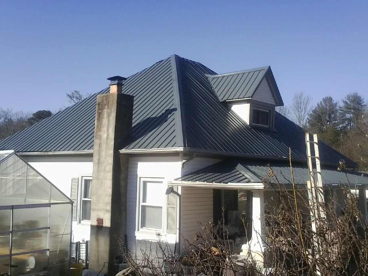 Dark blue standing seam metal roof on a white farmhouse with dormer — Slate & Tile Roof Repair by Roofing Brothers in Tillson