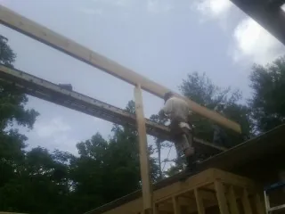 Carpenter setting a ridge beam over a new addition frame — Ice Dam Removal by Roofing Brothers in Tillson