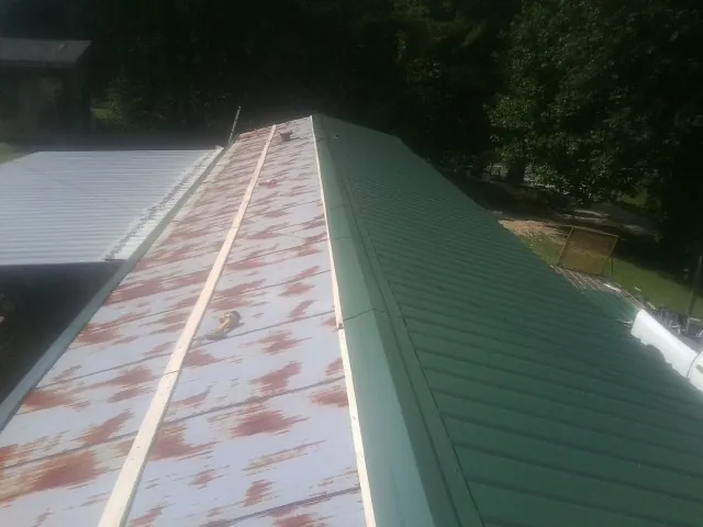 Old rusted panels beside newly installed green metal roofing — Wind Damage Roof Repair by Roofing Brothers in Tillson