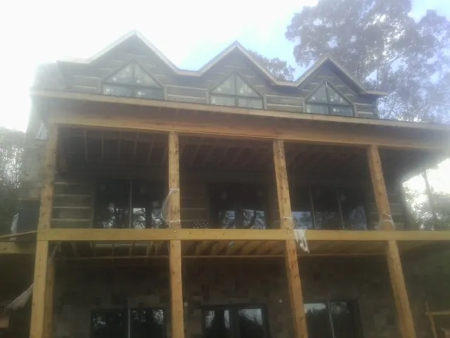 Dormers and porch framing on a large log home under construction — Roof Coating work by our crew in Tillson